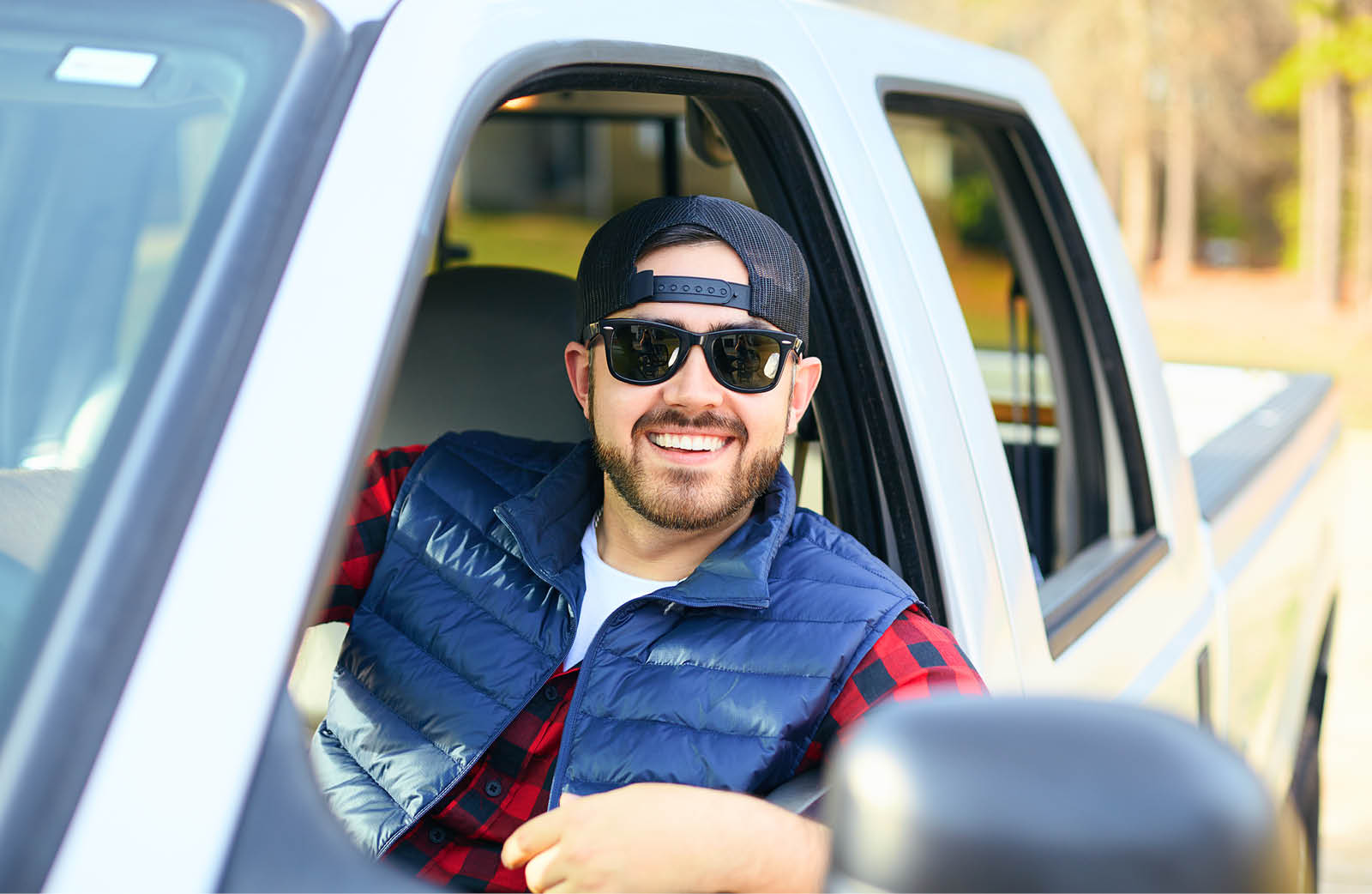 Image of a man in a truck smiling with sunglasses on